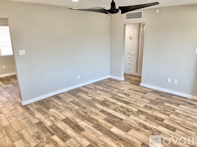 A room with a ceiling fan and wooden flooring.