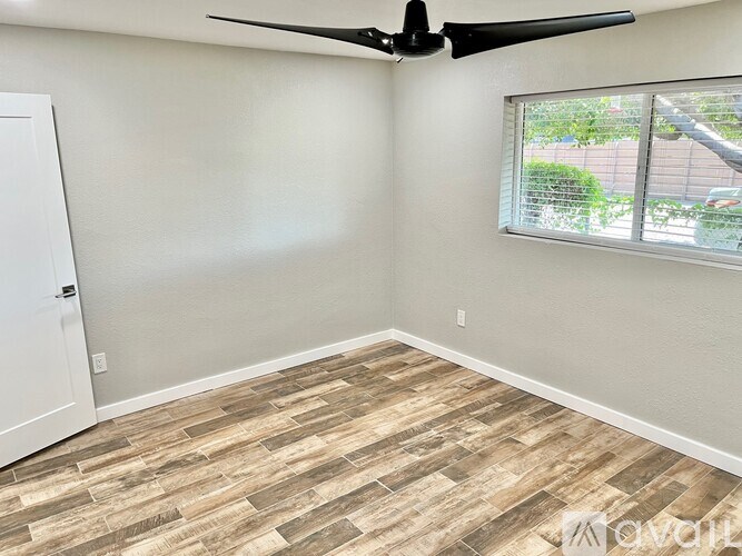 A room with a ceiling fan and a window with blinds.