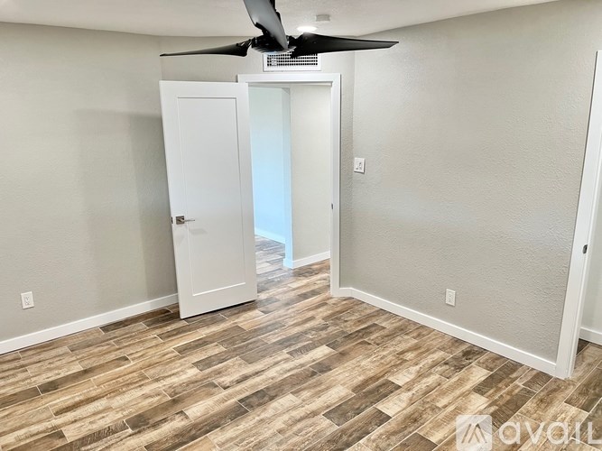 A room with a ceiling fan and a door leading to a balcony.