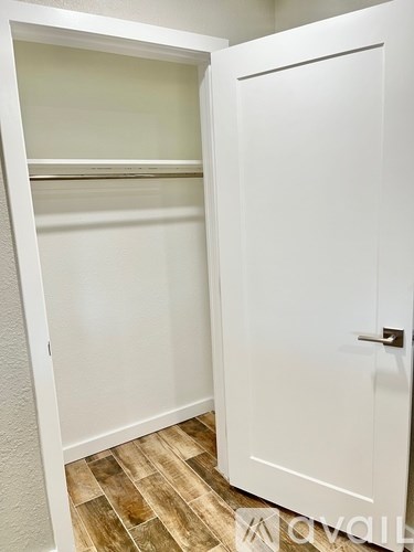 A white closet with a door and shelves.
