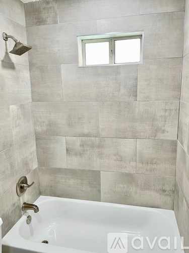 A bathroom with a tub and a window.