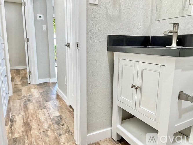 A bathroom with a wooden floor and white cabinetry.
