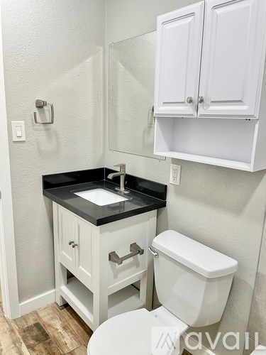 A white toilet sits under a white cabinet in a bathroom.