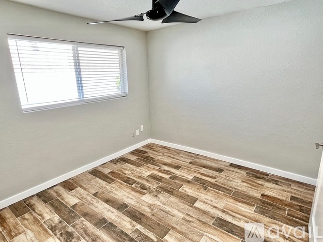 A room with a ceiling fan and a window with blinds.