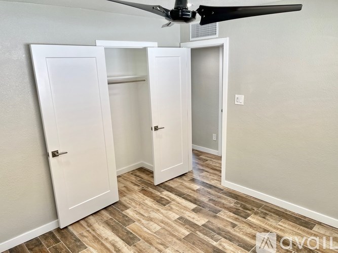 A room with a ceiling fan and three white doors.