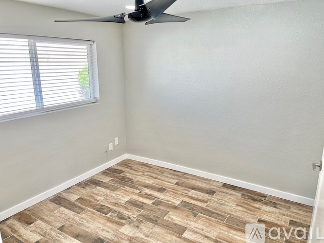 A room with a ceiling fan and a window with blinds.