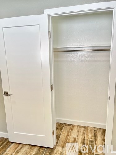 A white closet with a door open and a shelf inside.