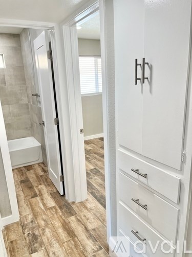 A white bathroom with a walk-in shower and a white cabinet with drawers.