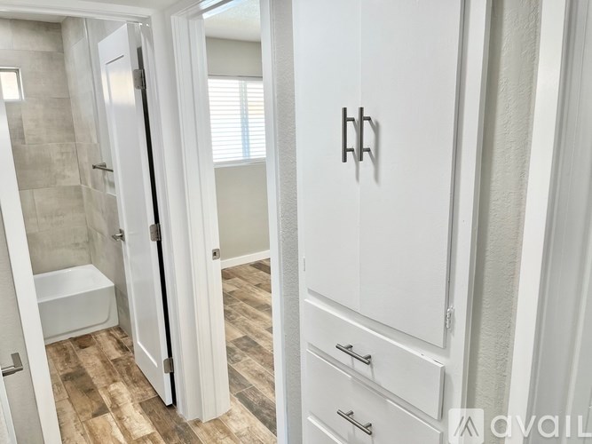 A white bathroom with a walk-in shower and a towel bar on the door.