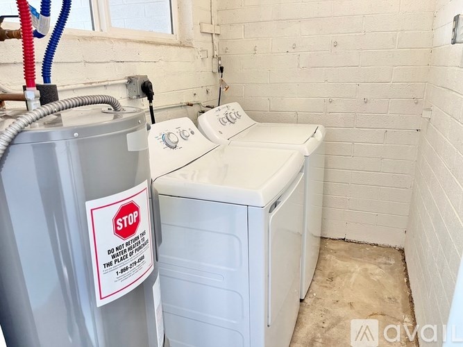 A bathroom with a washer and dryer and a sign on the washer that says stop.