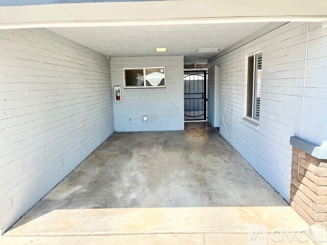 A white garage with a concrete floor and a brick pillar on the right side.