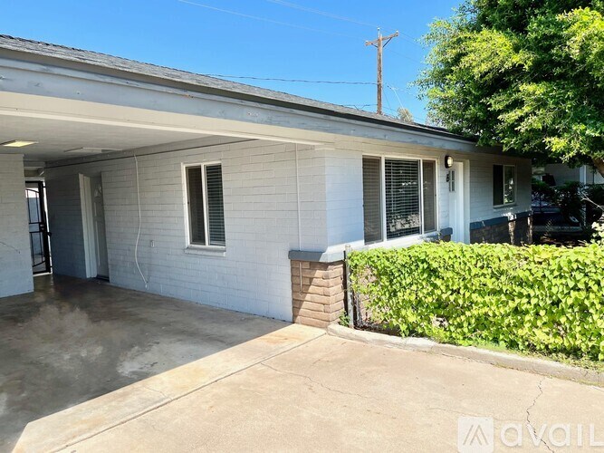 A house with a white exterior and a grey roof with a driveway in front.