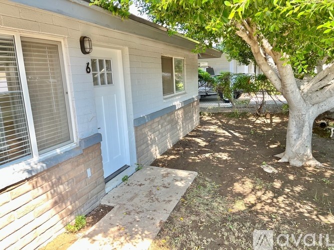 A house with a white door and a tree in front.