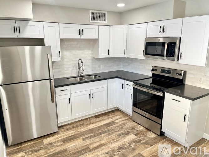 A kitchen with white cabinets and a stainless steel refrigerator.