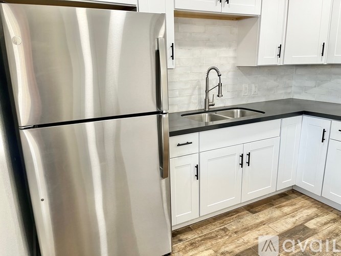A modern kitchen with a stainless steel refrigerator and white cabinets.