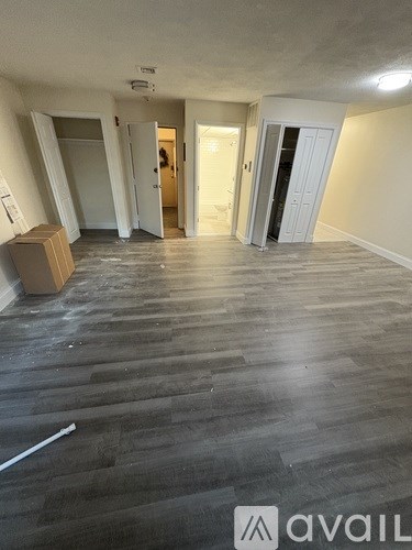A room with wooden flooring and a cardboard box on the floor.