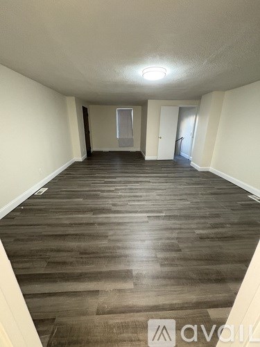 A long hallway with wood floors and white walls.
