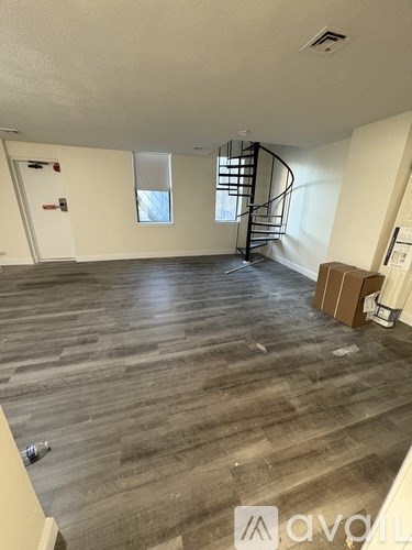 A room with wooden flooring and a spiral staircase.