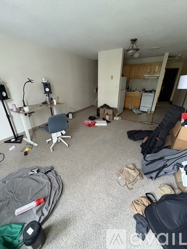 A room with a lot of clutter including a backpack, a chair, and a cardboard box.