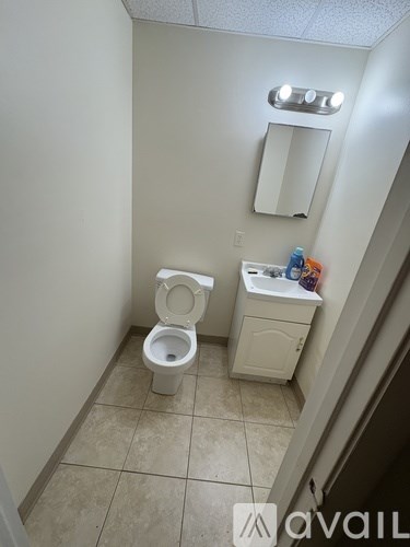 A small bathroom with a toilet, sink, and mirror.