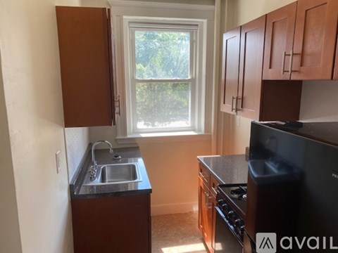A kitchen with brown cabinets and a black stove top oven.