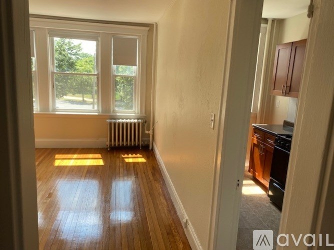 A room with wooden floors and a window overlooking a tree.