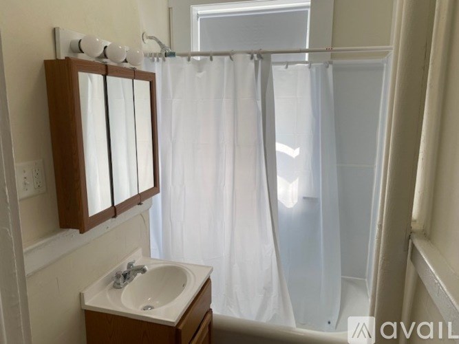 A bathroom with a sink, mirror, and shower curtain.