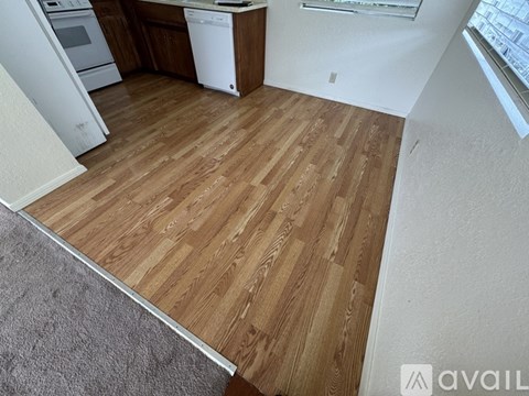 A kitchen with a white dishwasher and wooden flooring.