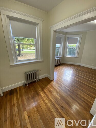 A room with wooden floors and a window with blinds.