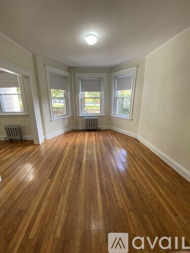 A room with wooden floors and three windows.
