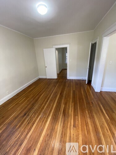 A room with wooden flooring and a doorway leading to another room.
