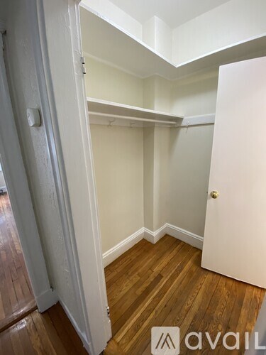 A room with a white door and a white wall with a skylight.