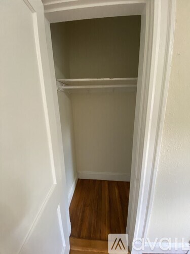 A white closet with a shelf and wooden floors.