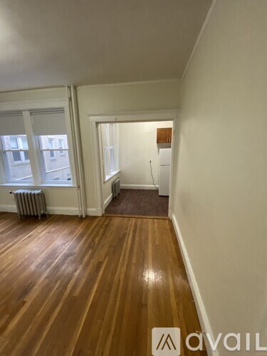 A room with wooden floors and a window with a radiator.