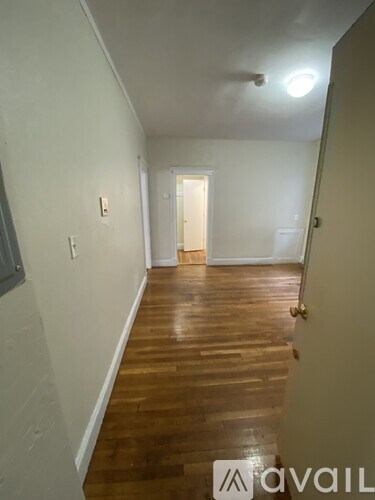 A hallway with wooden floors and white walls.
