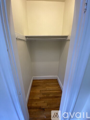 A small, empty room with wooden flooring and white walls.