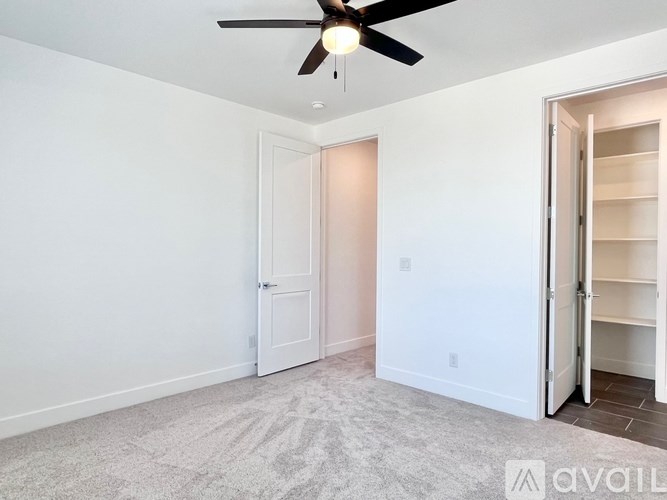 A room with a ceiling fan and two doors, one of which is open.