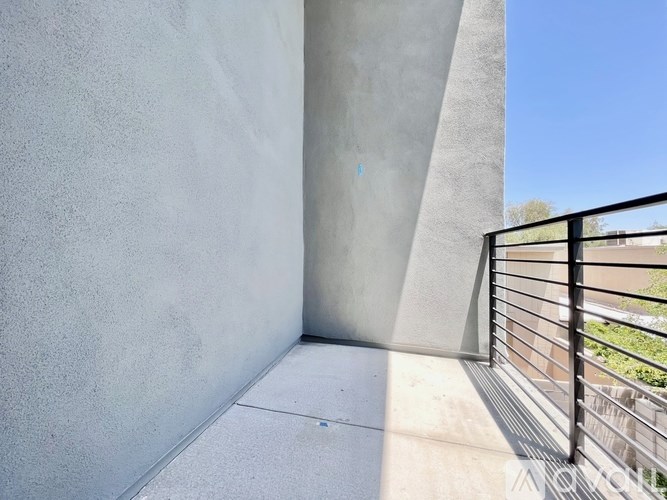 A balcony with a black railing and a concrete wall.