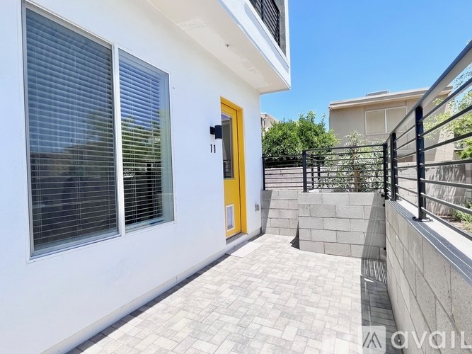 A white house with a yellow door and black railings.