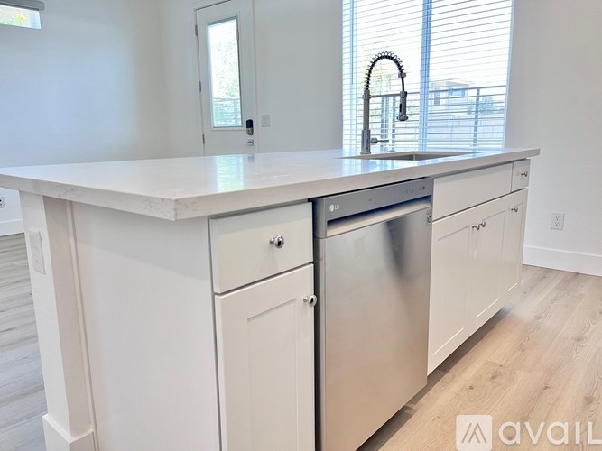 A white kitchen with a stainless steel dishwasher and a white countertop.