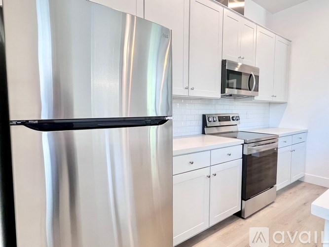 A kitchen with a stainless steel refrigerator and white cabinets.