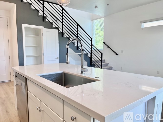 A kitchen with a white countertop and a stainless steel sink.