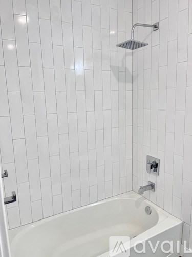 A white bathtub with a shower head above it.