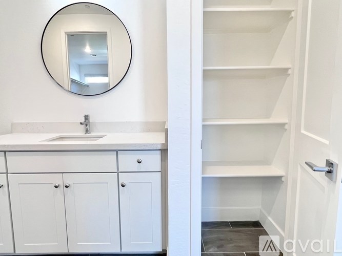 A bathroom with a white sink and a round mirror.