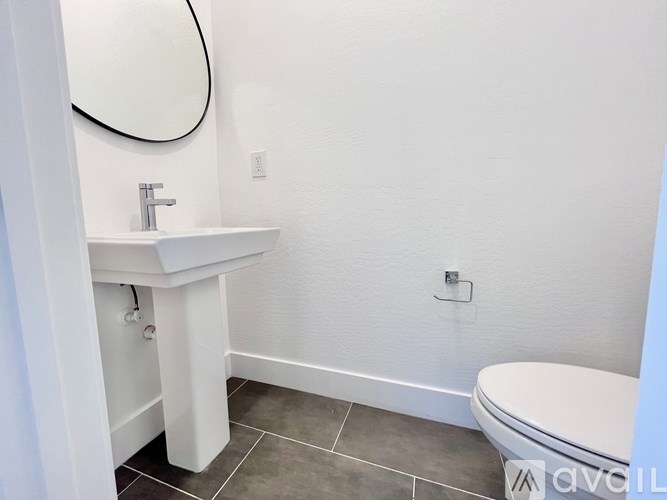 A bathroom with a sink, toilet, and mirror.