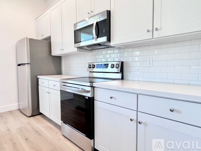 A kitchen with white cabinets and a black microwave above the stove.