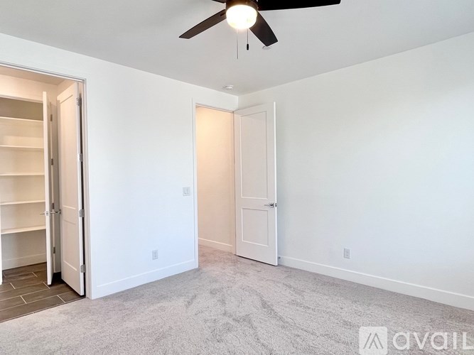 A room with a ceiling fan and two doors.