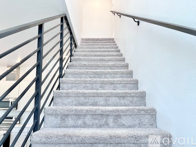 A staircase with a metal railing and carpeted steps.
