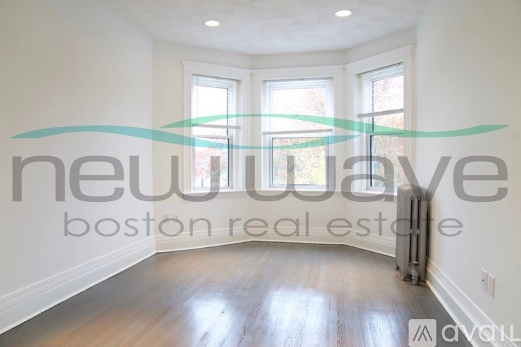 A room with a wooden floor and a window with a view of trees outside.