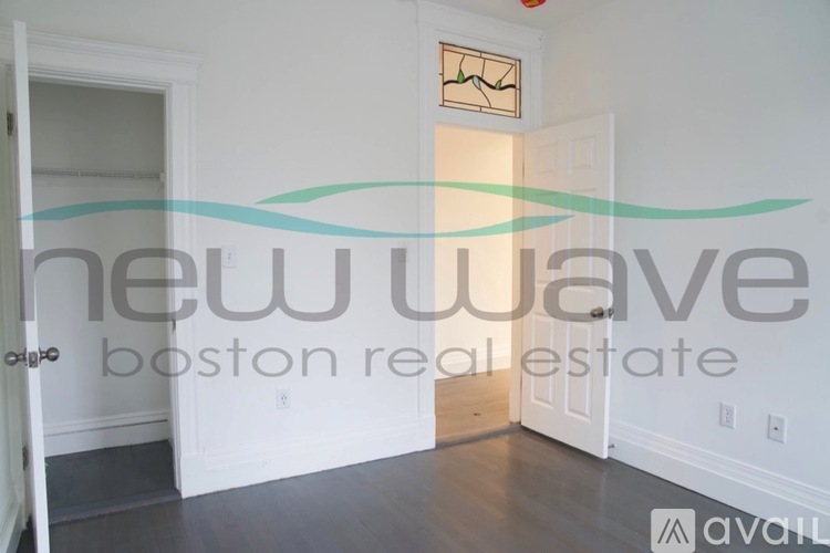 A room with a white door and a wall with a clock and a logo for New Wave Boston Real Estate.